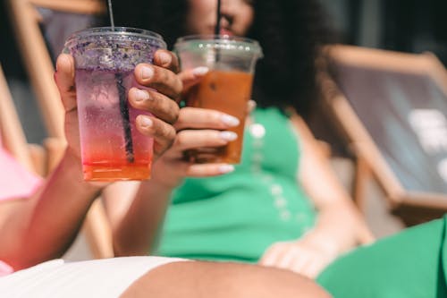 A Person Holding a Clear Plastic Cup with Drinks