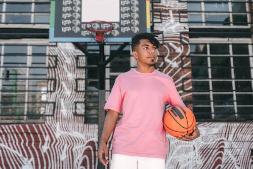 Man in Pink Crew Neck T-shirt Standing Near the Basketball Hoop