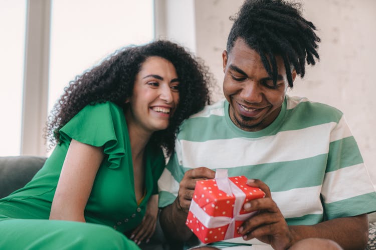 A Man Opening A Gift From A Woman