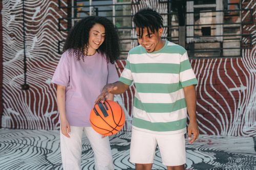 Free Happy interracial couple playing basketball in front of urban graffiti art wall. Stock Photo