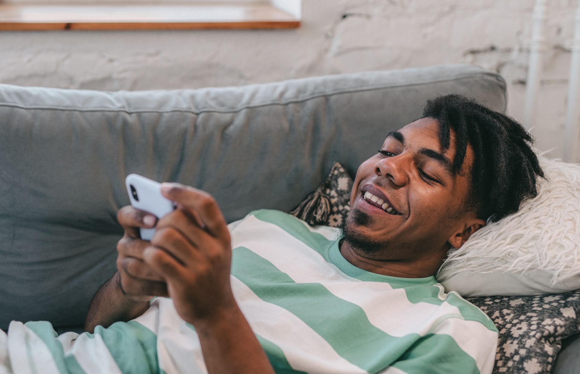 A Man using a Smartphone while Lying on the Sofa
