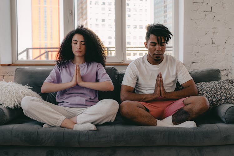 Man And Woman Sitting On A Couch Meditating