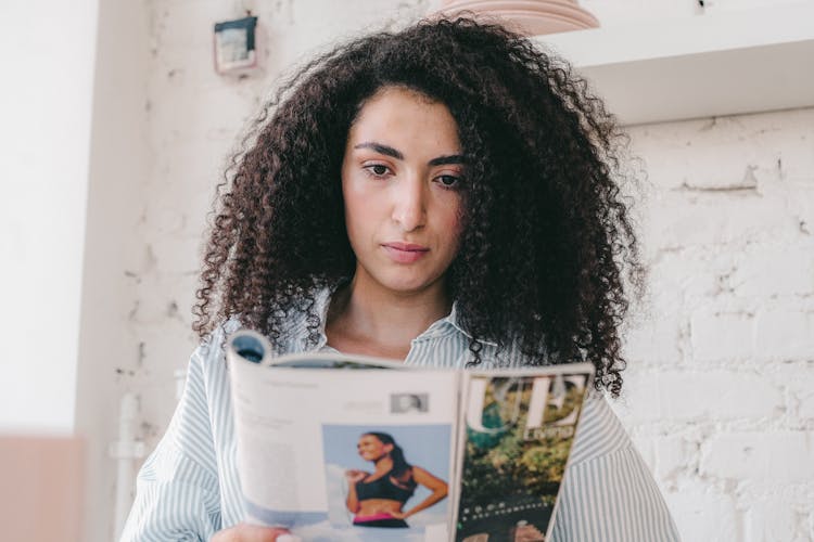 A Woman With Curly Hair Reading A Magazine
