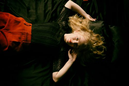 Free Studio portrait of a blonde woman in a black lace top lying on black satin. Stock Photo