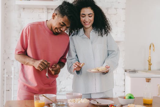 Smiling couple with curly hair sharing a cozy breakfast indoors, enhancing relationship joy.