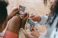 An interracial couple reminisces over cherished Polaroid moments on a wooden floor.