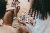 A couple sits together indoors reviewing a collection of printed photos, exemplifying nostalgia and shared moments.