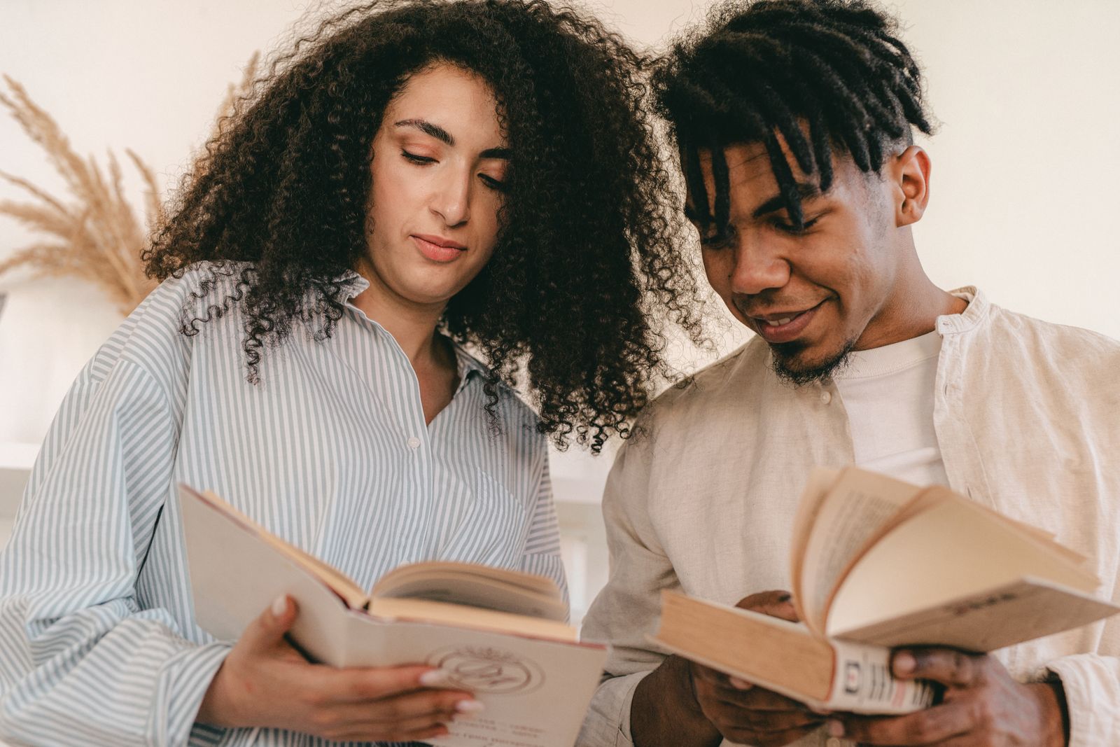 Two people reading books together at home