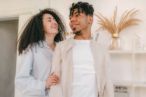 Free Smiling couple sharing a loving moment indoors with natural decor. Stock Photo
