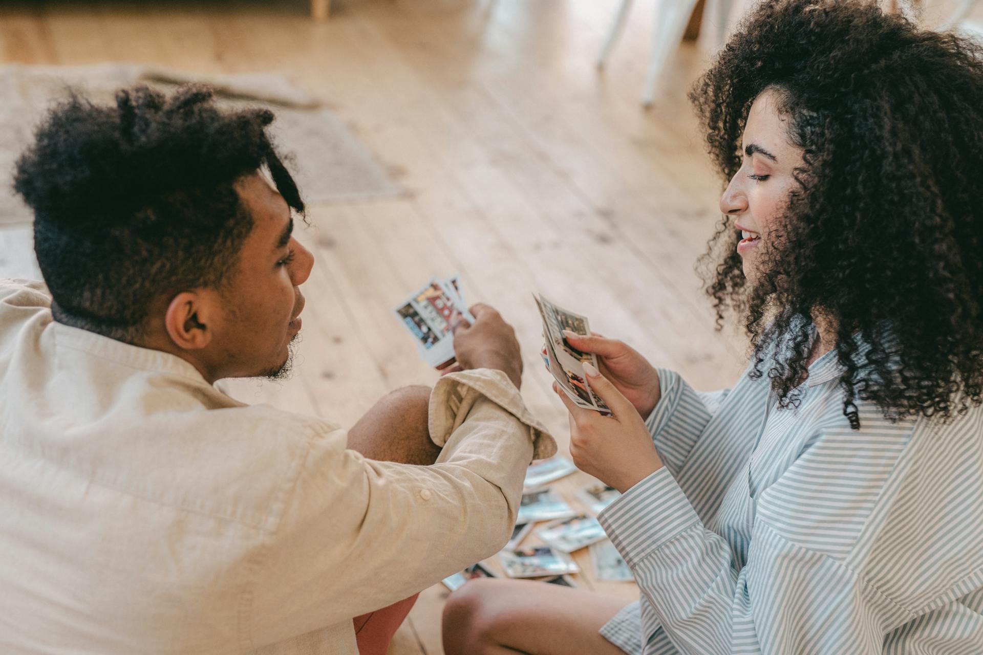 Man and Woman Sitting on the Floor Looking at their Photos