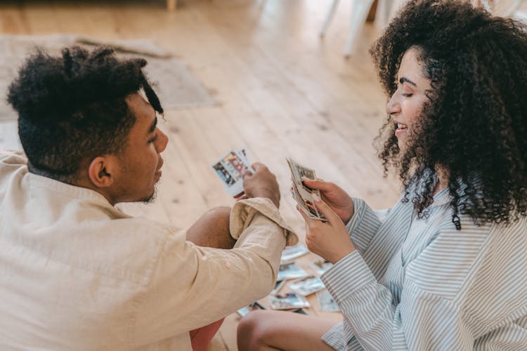 Man And Woman Sitting On The Floor Looking At Their Photos 