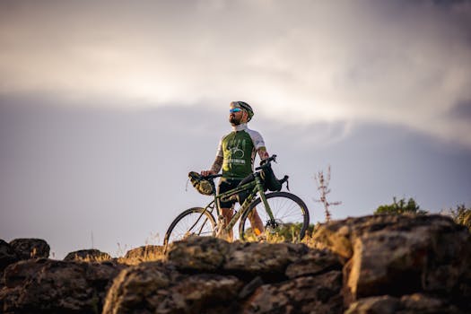 An adventurous cyclist poses on rocky terrain in Türkiye during a vibrant sunset.