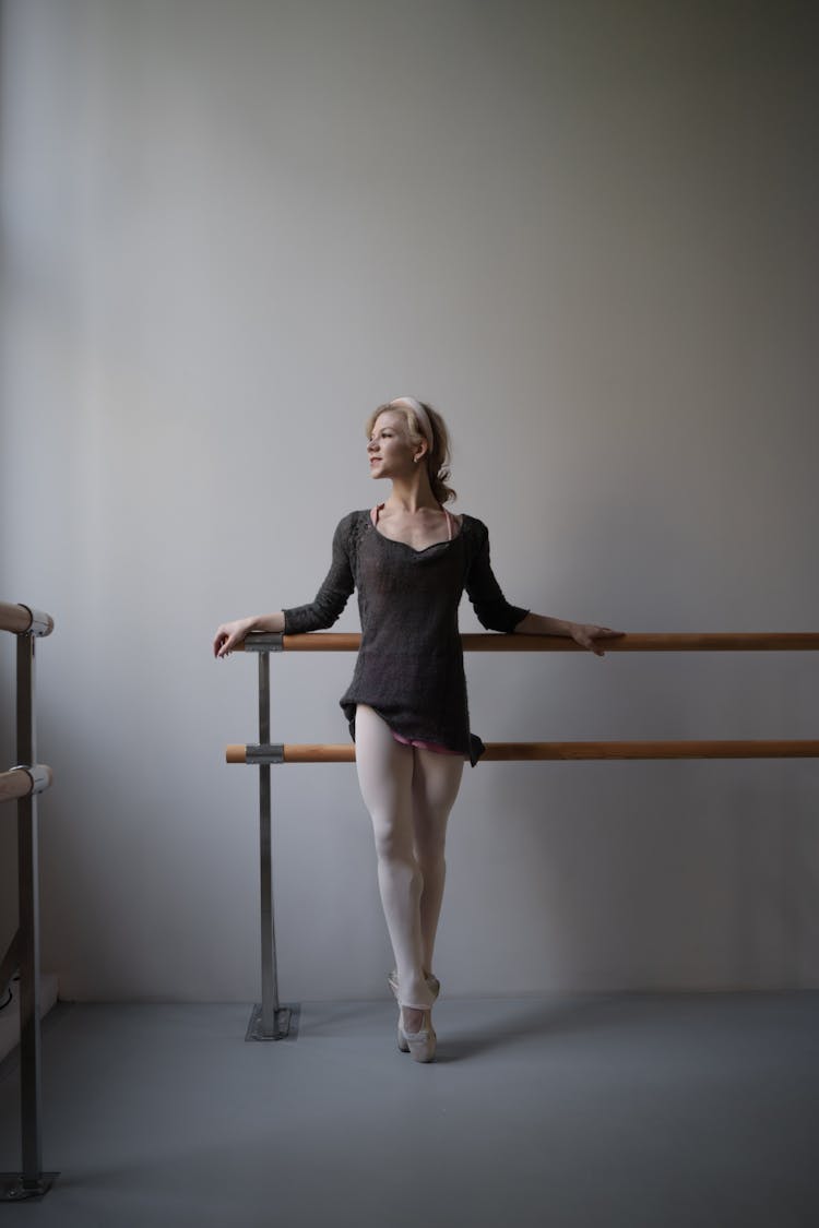 A Ballet Dancer Leaning On Ballet Bar