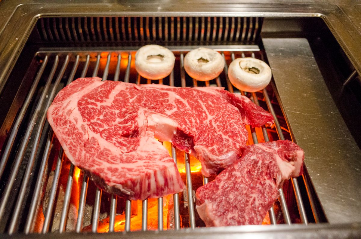 Marbled wagyu beef steaks sizzling on a grill showing marbling and grill marks