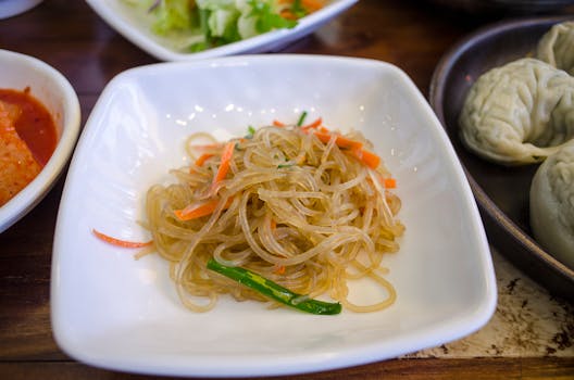 Delicious Korean glass noodles served with vibrant vegetables in a ceramic dish, perfect for a savory meal.