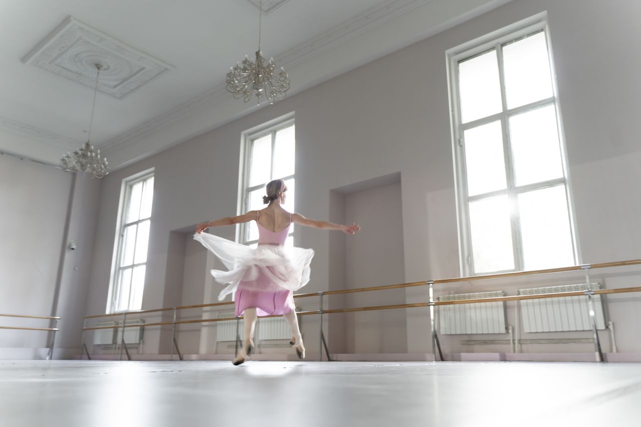a graceful ballerina practicing ballet movements in a bright sunlit da
