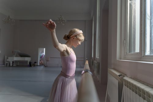 Free Woman in Pink Ballet Costume Standing Near a Bar Stock Photo