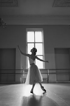 Elegant ballerina posing gracefully in a monochrome ballet studio setting.