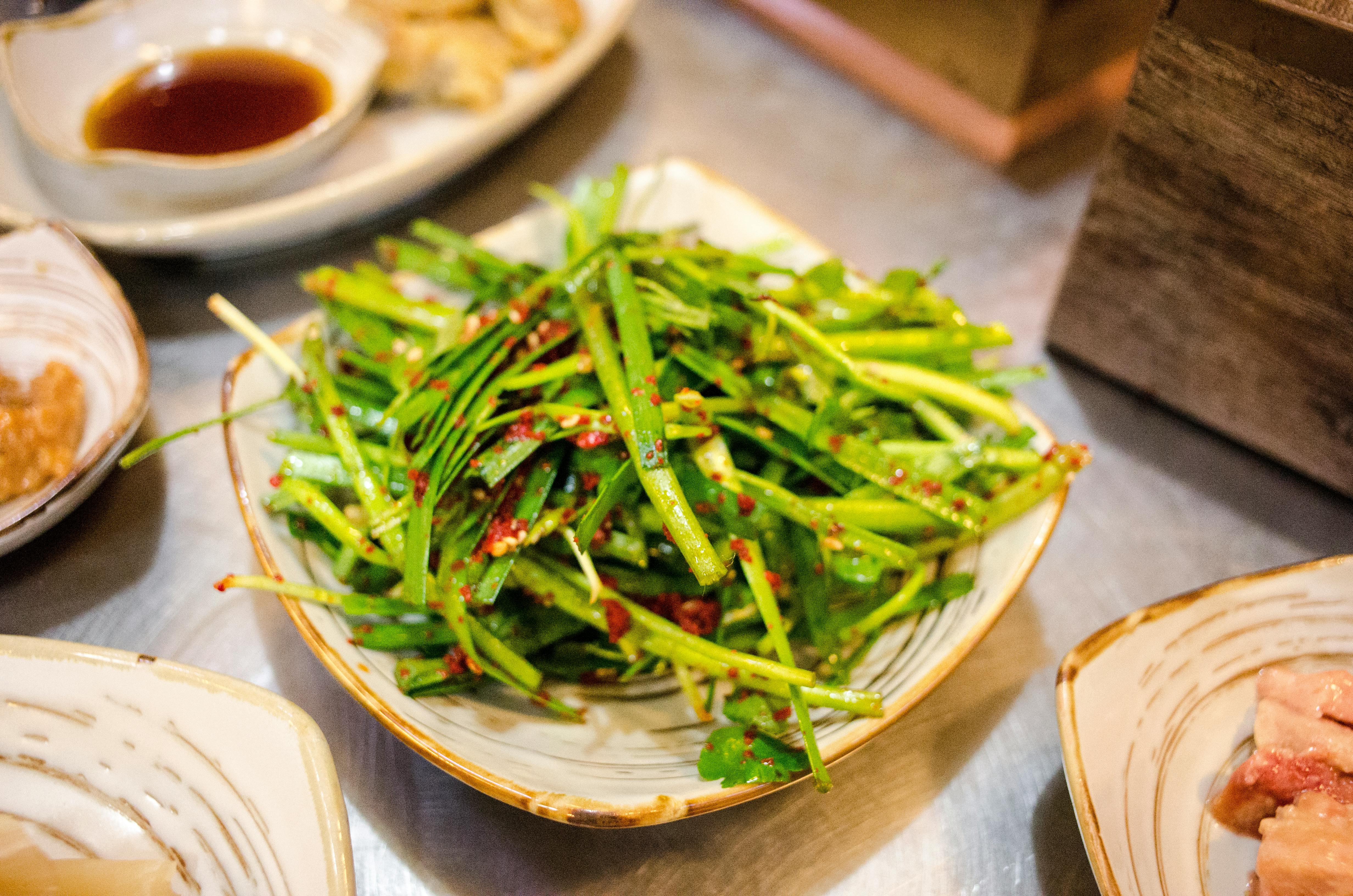 Delicious green chive salad with spicy seasoning served on a ceramic plate. Perfect for healthy meals.