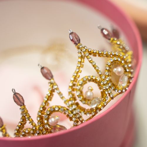 Free Close-up of a luxurious golden crown adorned with pearls in a pink box, representing elegance and royalty. Stock Photo