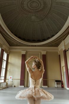 A ballet dancer gracefully poses in an ornate dance studio with a domed ceiling.
