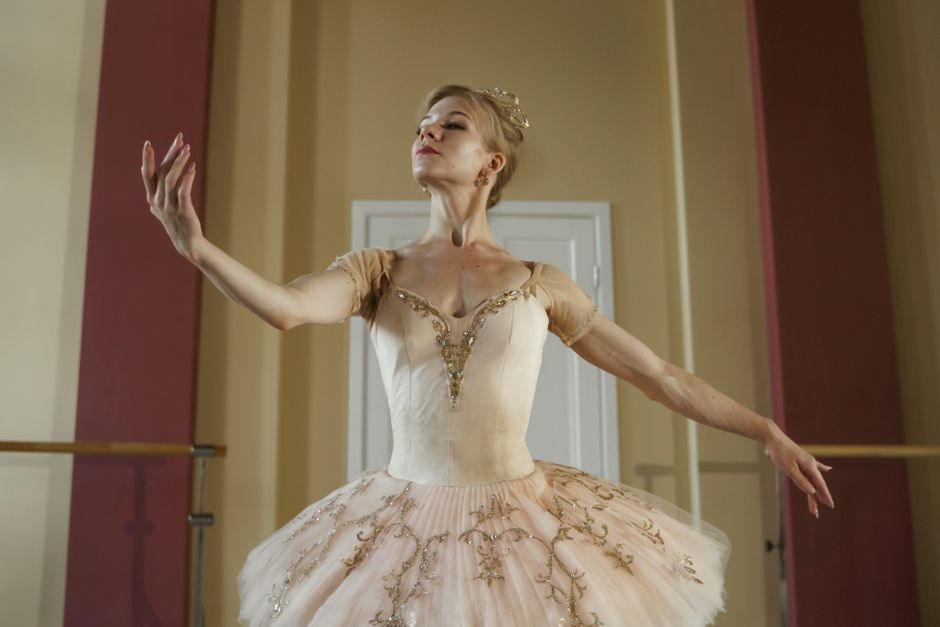 Graceful ballerina in pink tutu performing a pose indoors.