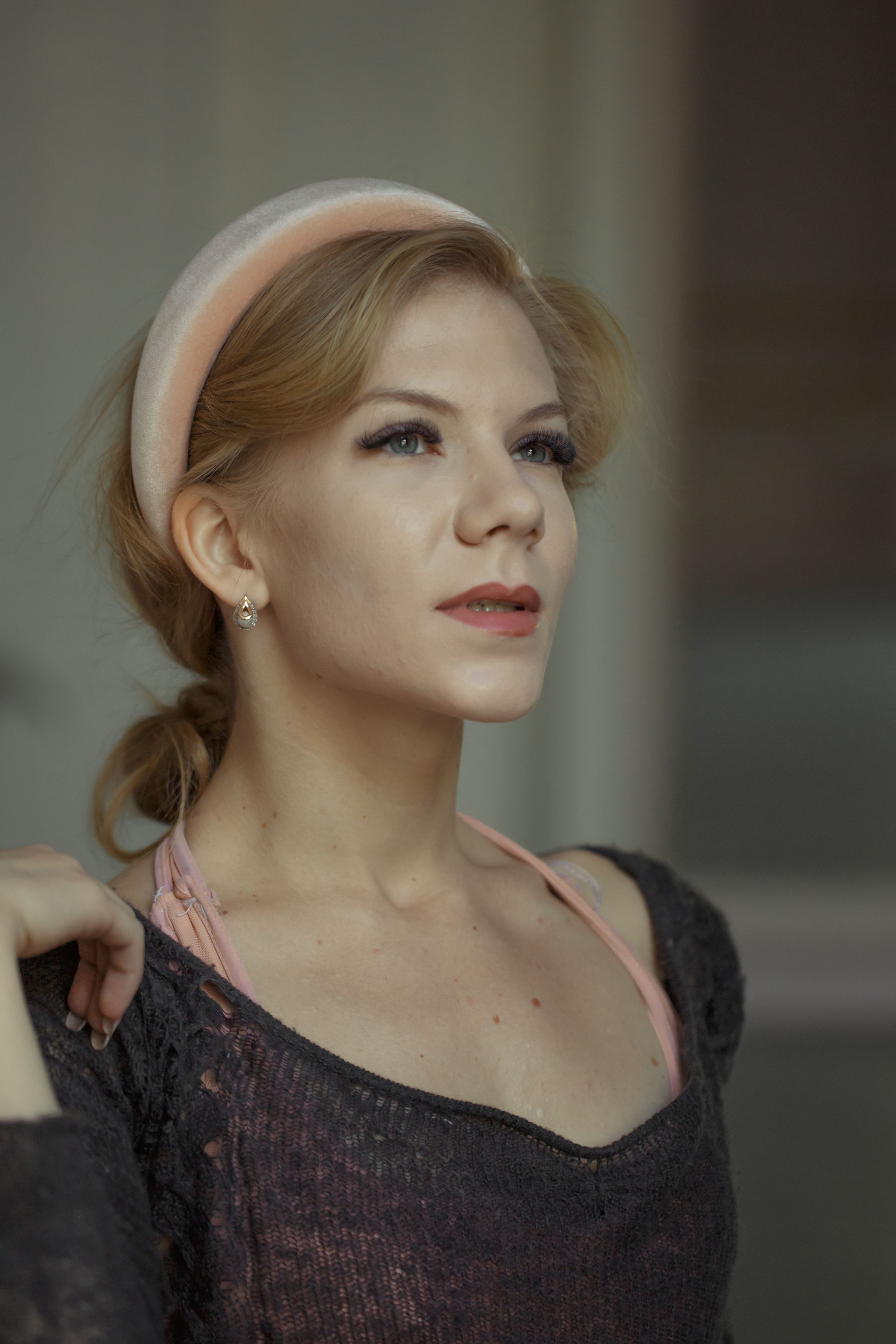 Portrait of a stylish woman with a foam headband, exuding elegance and confidence indoors.