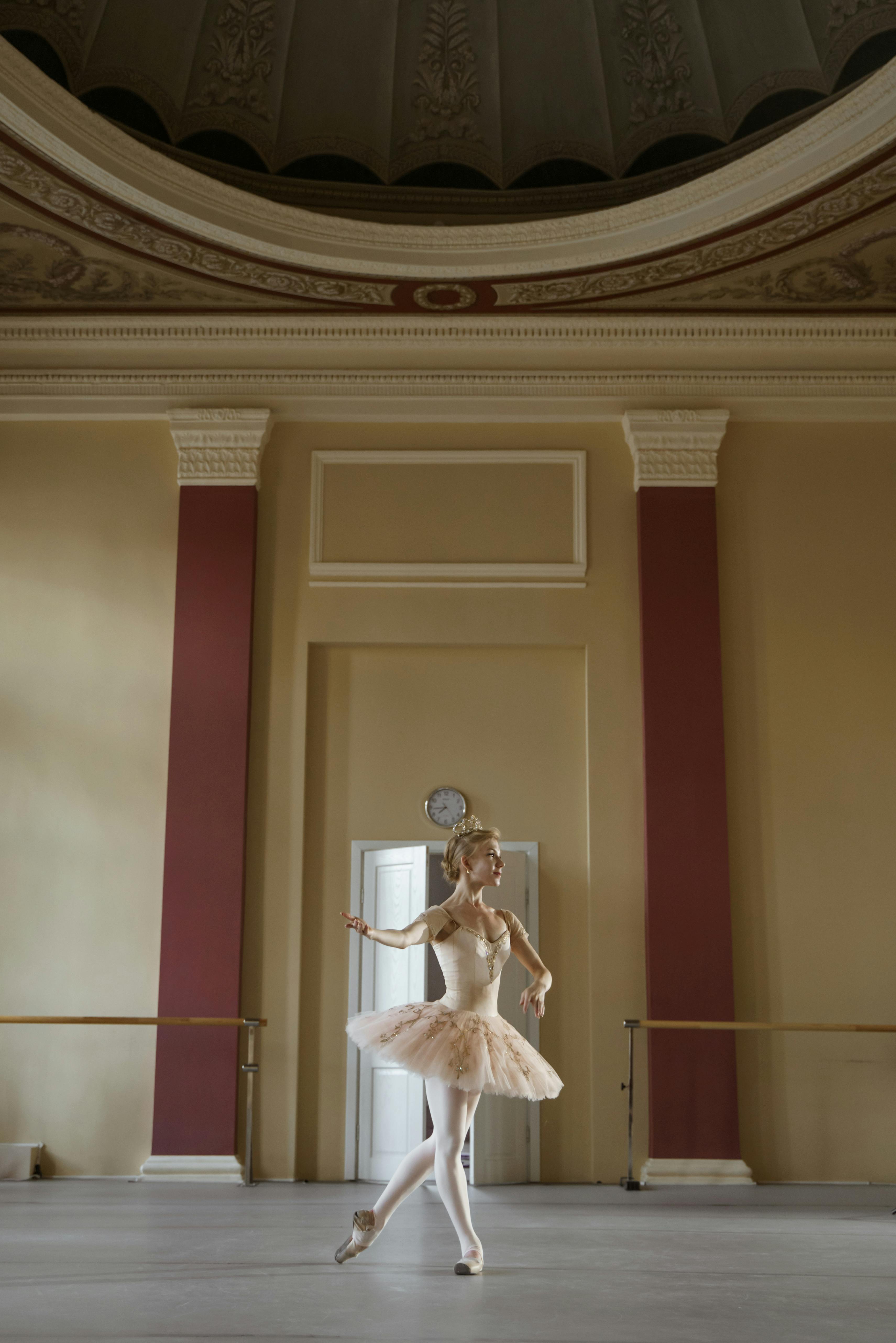Free Ballerina gracefully dances in a classic hall setting, showcasing poise and elegance. Stock Photo