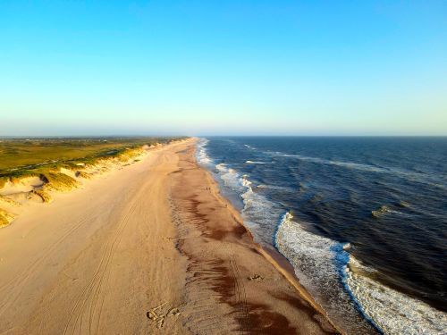 Free Stunning aerial shot of Hvide Sande beach with crashing waves and golden sands. Stock Photo