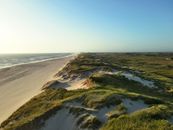 Explore the tranquil dunes and coastline of Hvide Sande, Denmark, bathed in warm daylight.