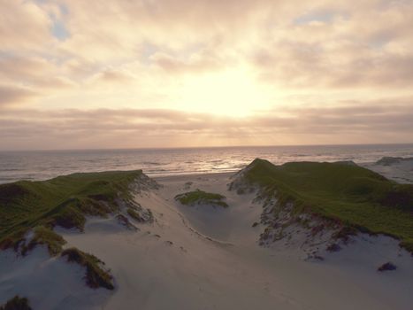 Experience the serene beauty of a sunset over sandy dunes at Hvide Sande beach, Denmark.