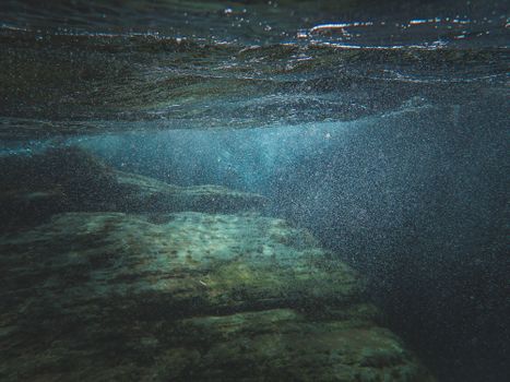 Explore the tranquil underwater world with rocks and sunlight filtering through water.