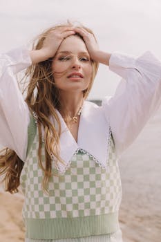 Stylish woman with long hair posing outdoors near a river.