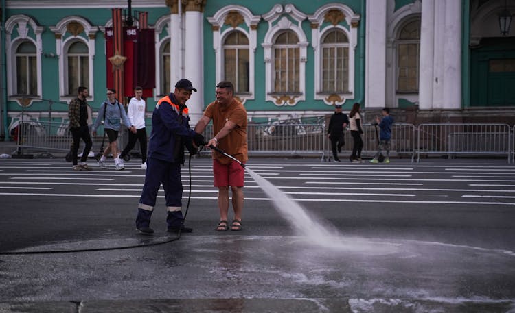 A Worker Hosing Down The Street