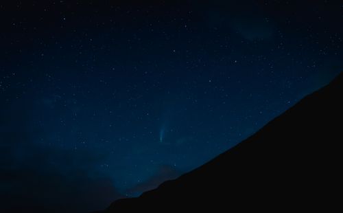 Free Stunning night sky full of stars above a dark mountain silhouette, creating a serene and awe-inspiring scene. Stock Photo