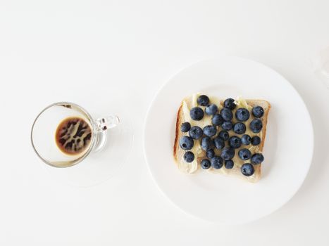 A delicious blueberry toast paired with a clear cup of coffee on a white background.