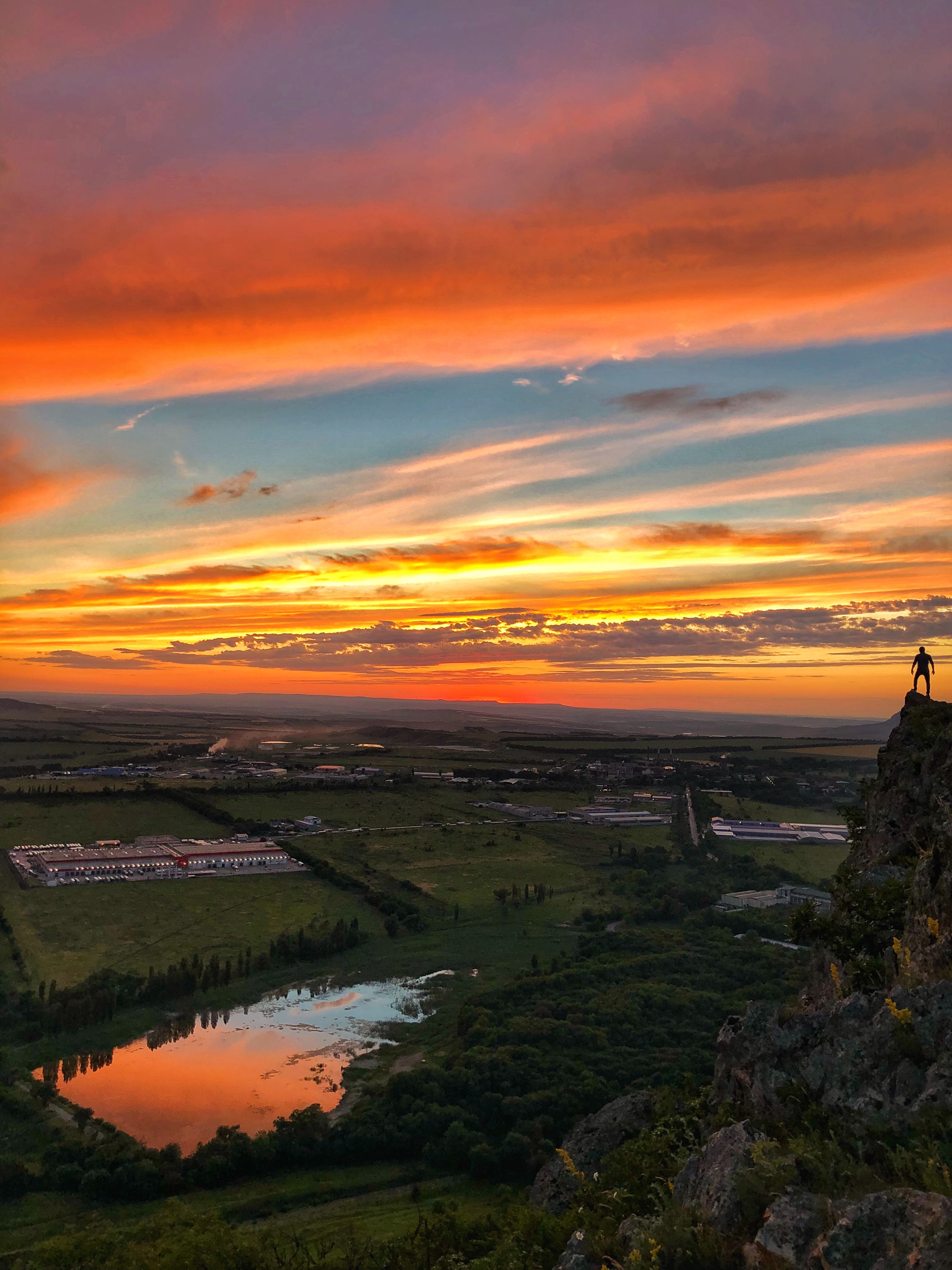 Vibrant sunset over the countryside in Stavropol, Russia, with a climber on a cliff.