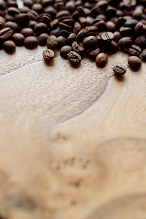 Free Close-Up Shot of Roasted Coffee Beans on Wooden Surface Stock Photo