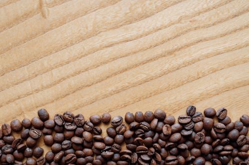 Free Aromatic roasted coffee beans spread across a wooden surface, perfect for barista themes. Stock Photo