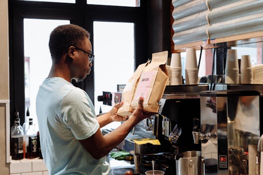 A barista in a white shirt operates an espresso machine, preparing coffee in a modern café.