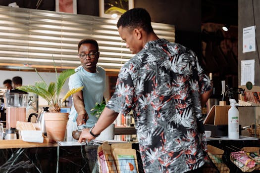 Two men engage in a friendly conversation at a stylish indoor coffee shop counter.