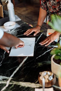 Hands pointing to a menu on a polished black countertop in a stylish store setting.