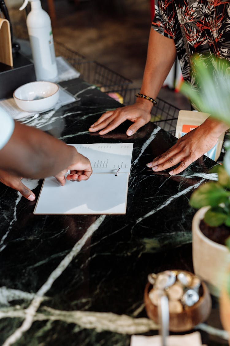 A Person Pointing To A Menu