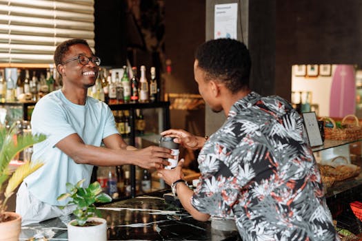 Smiling customer receives a takeaway coffee from a cheerful barista in a lively cafe.