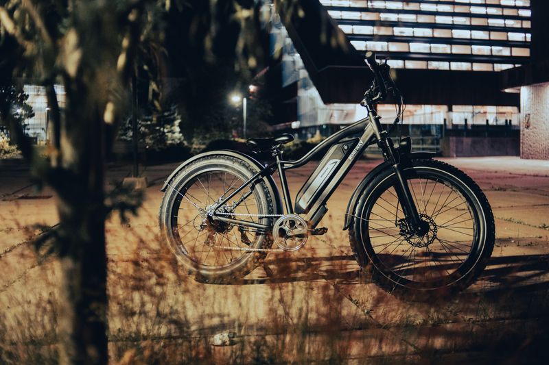 A sleek electric bike is parked on a city pavement, illuminated by streetlights at night.