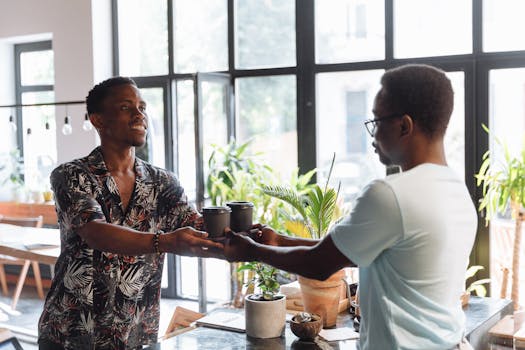 Two men exchanging coffee cups in a lively and modern cafe interior.