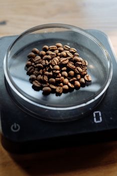 Coffee beans in a glass dish on a digital scale, perfect for coffee enthusiasts.