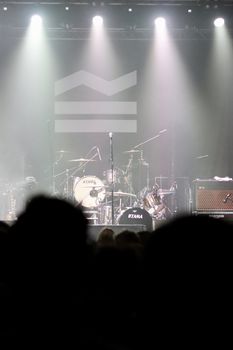 Empty concert stage with drum set under vibrant spotlights, ready for performance.