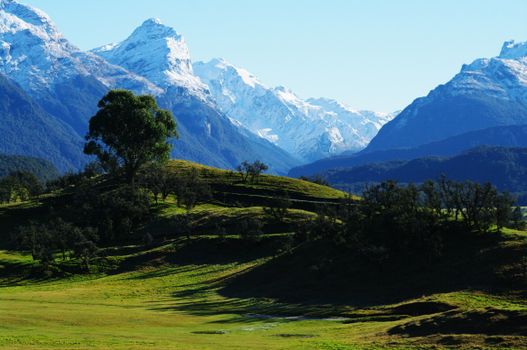 Breathtaking view of snow-capped mountains and lush valleys in New Zealand's scenic landscape.