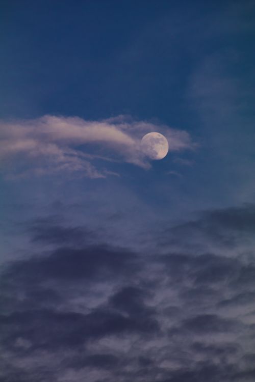 Free Full moon emerging through dark clouds in a serene night sky. Stock Photo